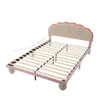A pink and beige upholstered bed frame with a scalloped headboard and wooden slats, shown from a diagonal angle against a white background. Náhled obrázku produktu