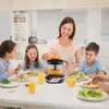 A family is having a meal at a table, and the mother is using an electric juicer to make orange juice. Produktbild-Vorschau