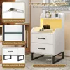 A white nightstand with two drawers and an open shelf, featuring LED lighting, is shown in a room setting. Insets highlight stability features like an anti-tip device, reinforced crossbar, and elevated legs. Text describes features and benefits. Anteprima dell’immagine prodotto