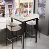 A bar table with two stools set up in a cafe-like setting, with a backdrop of shop windows and a street scene. Náhľad obrázku produktu