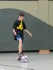 A young boy is playing soccer indoors. Anteprima dell’immagine prodotto