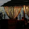People sitting under a gazebo decorated with icicle lights. Anteprima dell’immagine prodotto