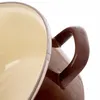 A close-up view of the handle and rim of a brown and beige pot. Voir les images du produit