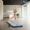 A woman is performing a yoga pose on an inflatable air track mat in a bright, modern room. Náhled obrázku produktu