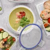 A top-down view of food containers filled with food, including soup and meatballs, arranged on a textured surface. Náhled obrázku produktu