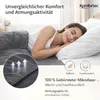 A woman sleeping peacefully on a bed with a grey bedsheet and white pillow. Produktbild-Vorschau