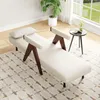 A cream-colored lounge chair with wooden accents is placed on a patterned rug in a well-lit room with a large window. Náhled obrázku produktu