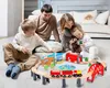 A family playing with a wooden train set on the floor. Produktbild-Vorschau