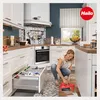 A woman is cleaning the floor in a modern kitchen. Produktbild-Vorschau