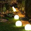 A garden path illuminated by spherical lights at night. Anteprima dell’immagine prodotto