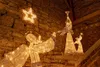 Christmas nativity scene with illuminated angel figures and a star against a stone wall. Voir les images du produit