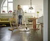 A young girl is cleaning the floor with a cordless floor cleaner in a bright, modern living room. Produktbild-Vorschau