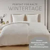 A bed with white bedding is shown, with text overlays suggesting it is perfect for cold winter days and creates a cozy atmosphere. Voir les images du produit