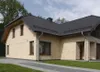 A modern house with beige stone facade and dark roof, with a driveway and lawn in front. Anteprima dell’immagine prodotto