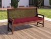 A wooden bench with a red cushion is placed on a wooden deck outdoors, with greenery and a building in the background. Produktbild-Vorschau