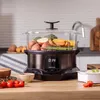 A steaming appliance filled with vegetables sits on a kitchen counter, with fresh produce in the foreground. Náhled obrázku produktu