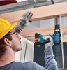 A person wearing safety gear is using a cordless drill to attach a wooden beam to a metal bracket. Náhled obrázku produktu
