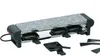 A raclette grill with a stone top and four individual cooking pans underneath, along with several spatulas. Produktbild-Vorschau