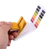A hand holding a booklet of pH test strips with a color chart. Produktbild-Vorschau