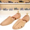 Two wooden shoe trees are displayed on a white background, with a blurred background of shoes on shelves. Náhľad obrázku produktu