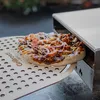 A pizza is being placed into a pizza oven using a pizza peel. Podgląd zdjęcia produktu