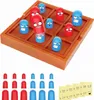A tic-tac-toe game with cartoonish pieces on a wooden board, with extra pieces and stickers shown below. Náhled obrázku produktu