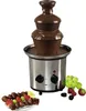 A chocolate fountain with chocolate flowing down the tiers, surrounded by fruits and chocolate-dipped items. Podgląd zdjęcia produktu