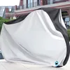 A motorcycle cover is shown outdoors on a paved surface, with a building in the background. Náhľad obrázku produktu