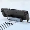 A gaming console is docked to a USB-C hub, with various cables laid out in front. Produktbild-Vorschau