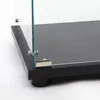Close-up of the base and lower corner of a glass display cabinet, showing the black base, glass panels, and metal hinges. Produktbild-Vorschau
