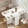 A white folding dining table with chairs set up for a meal, near a window. Produktbild-Vorschau
