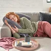 A woman is sleeping on a couch with a large pillow. Produktbild-Vorschau