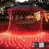 Red net lights are draped over a gazebo and spread across a wooden deck, with a house decorated for Christmas in the background. Produktbild-Vorschau