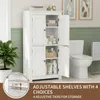 A white bathroom cabinet is shown open, with shelves displaying various toiletries and towels. A toilet is visible to the right. A plant is on the left. A close-up of shelf adjustment options is in the bottom left corner. Produktbild-Vorschau