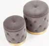 Two gray tufted ottomans with gold bases are shown against a white background. Produktbild-Vorschau