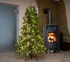 A decorated Christmas tree with lights in a cozy room with a fireplace. Náhľad obrázku produktu