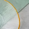 A close-up shot of a glass plate with a gold rim, placed on a gray surface next to a green napkin. Podgląd zdjęcia produktu