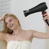 A woman is drying her hair with a hairdryer. Produktbild-Vorschau