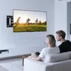 A couple sits on a couch watching a TV mounted on the wall. Produktbild-Vorschau