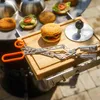 A close-up shot of a grill tongs and a cutting board with a burger and burger buns, set up for grilling. Podgląd zdjęcia produktu