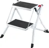 A white, two-step folding stepladder with black non-slip treads is shown against a white background. Podgląd zdjęcia produktu