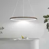 A modern ring-shaped pendant light hangs above a desk with a small decorative bird figurine and some papers. Náhled obrázku produktu