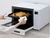 A person is removing a tray of cooked food from a microwave oven. Produktbild-Vorschau
