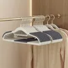 A set of grey and white non-slip hangers are neatly arranged on a golden clothes rail in a closet. Náhľad obrázku produktu