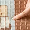 A finger is pressing down on a textured mat, showing its flexibility. Produktbild-Vorschau
