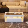A modern living room scene with a white coffee table in the foreground and a sofa in the background. Produktbild-Vorschau