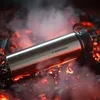 A metal thermos bottle lying on glowing embers and smoke. Produktbild-Vorschau