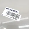 A close-up of a label with a barcode and product information on a light gray surface. Produktbild-Vorschau