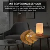 A lamp with a motion sensor is shown on a table next to a chair in a dimly lit room. Voir les images du produit