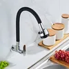 A kitchen faucet with a flexible black hose is mounted on a white tiled wall above a countertop. There are also some kitchen canisters and grapes visible. Náhľad obrázku produktu